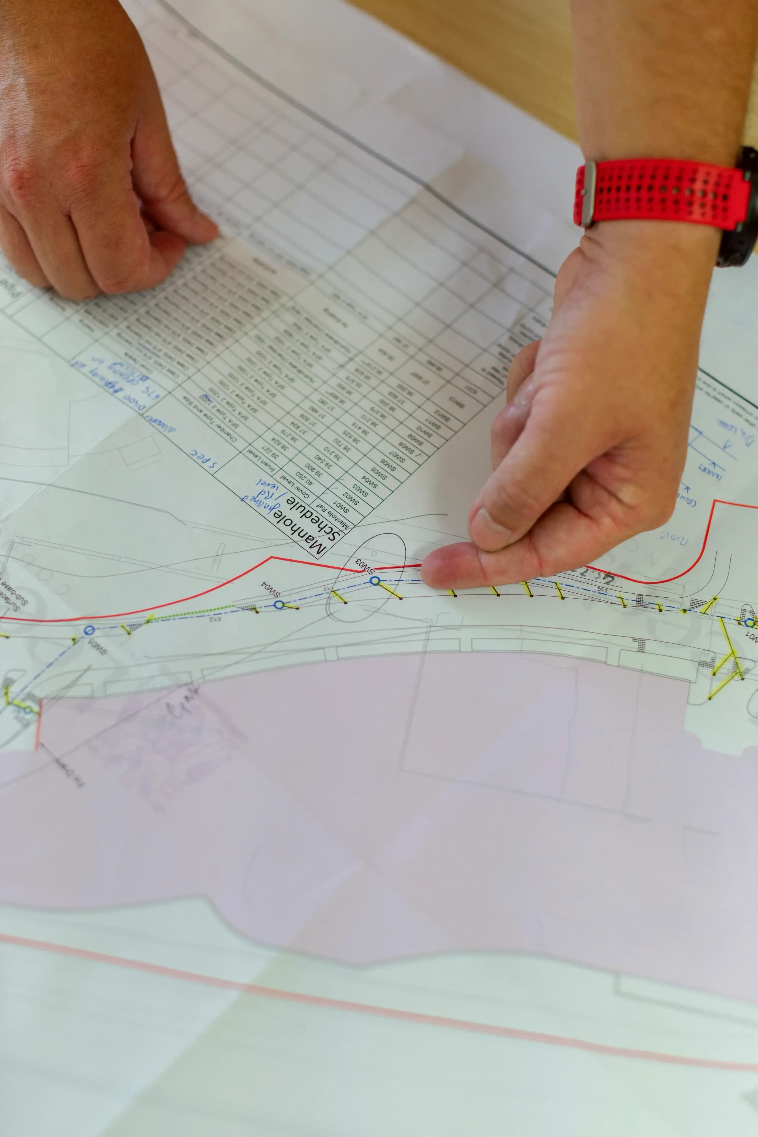 Hand zeigt auf einen Lageplan mit Schachtverzeichnis während der Bauplanung
