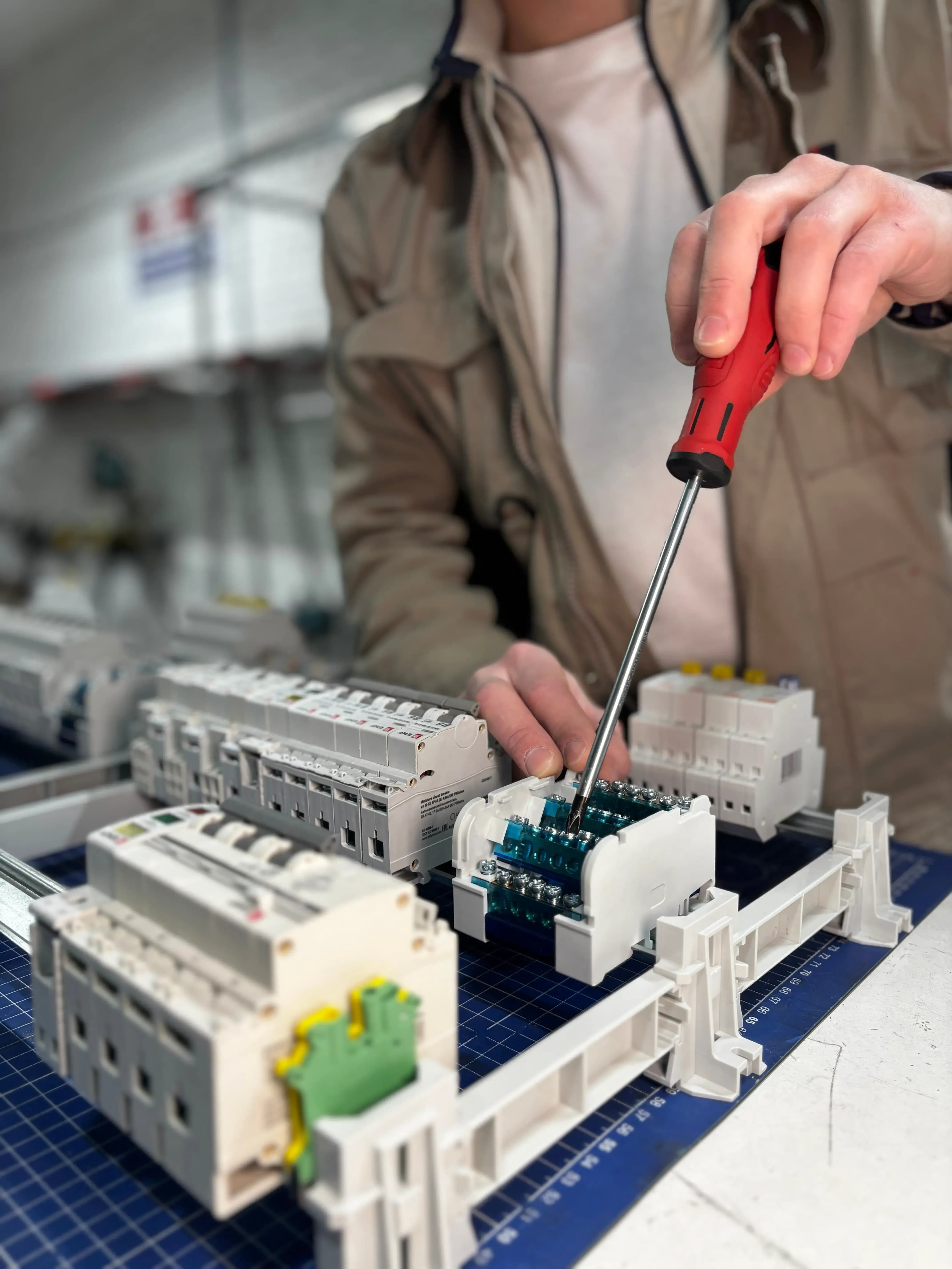 Elektriker montiert Sicherungen und Klemmen auf einer Hutschiene mit Schraubendreher